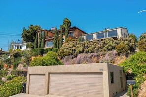 Un immobile residenziale con garage, un pendio vegetato e un cielo azzurro limpido.
