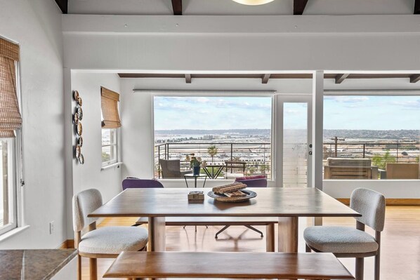 A dining area with a view of an airport, a large window, and a table with chairs.