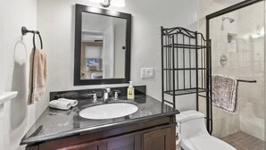 Une salle de bain avec un lavabo blanc, un miroir, un porte-serviettes et un espace douche.