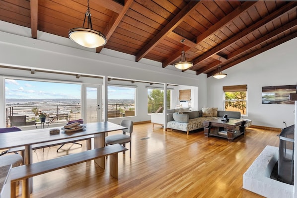 A spacious living area with a high ceiling, large windows, and a view of the cityscape.