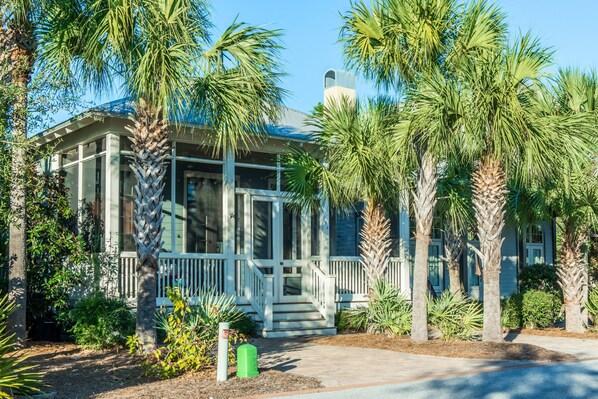 A house with a porch, surrounded by palm trees and various plants. - ☀️Close to Beach-Bikes-Community Pool-Surfin' Turtle (Santa Rosa Beach)