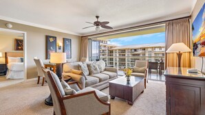 A hotel room with a balcony, a sofa, a coffee table, a TV, and artwork on the walls. - Maui Resort Rentals: Honua Kai Hokulani 649 - Upgraded 6th Floor 2BR, Fantastic Ocean Views! (Lahaina)