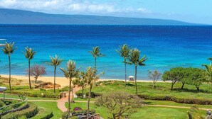 A tropical resort with a clear view of the ocean, palm trees, and a pathway leading to the beach. - Maui Resort Rentals: Honua Kai Hokulani 649 - Upgraded 6th Floor 2BR, Fantastic Ocean Views! (Lahaina)