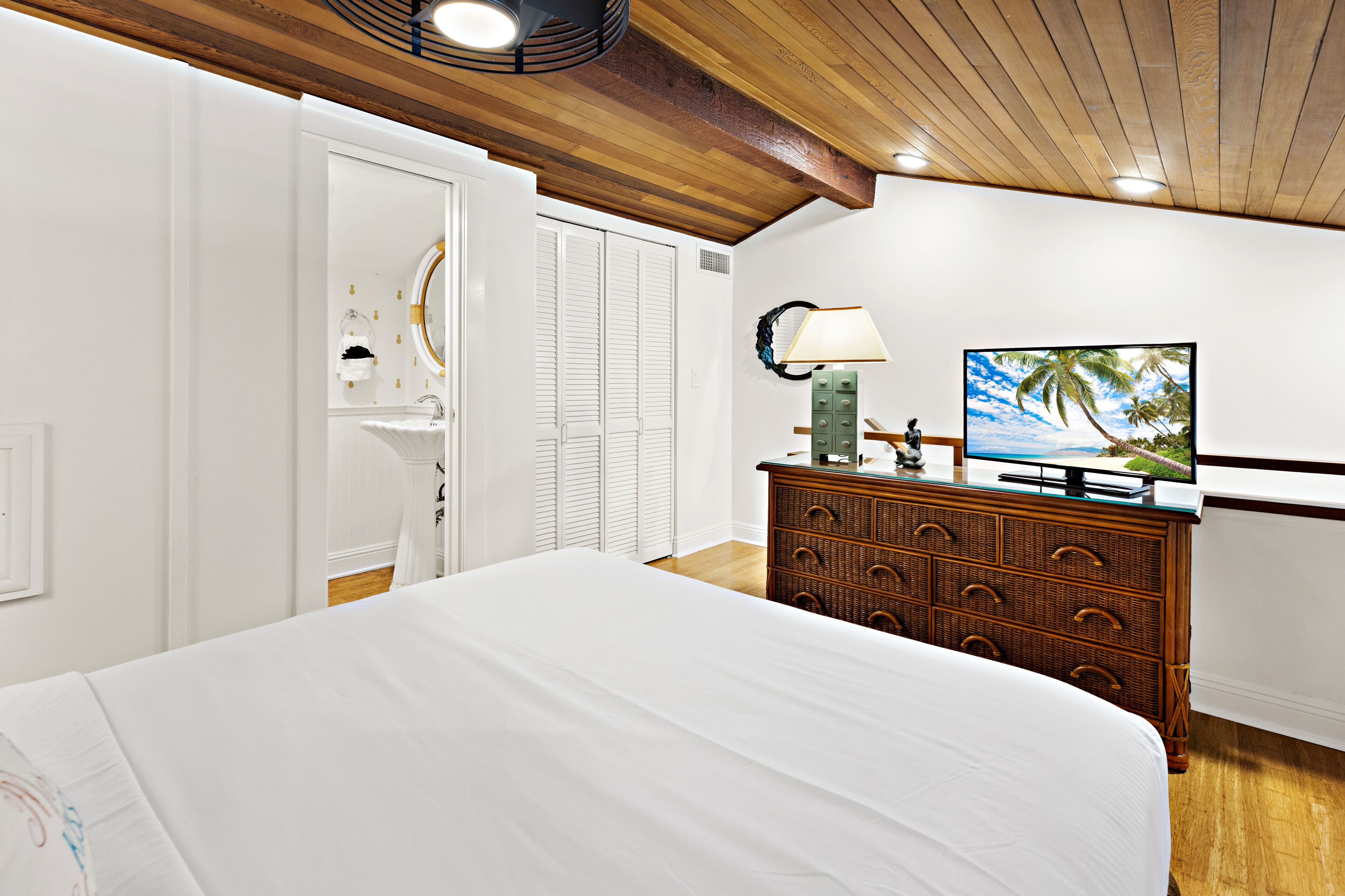 A bedroom with a bed, dresser, television, and a mirror.