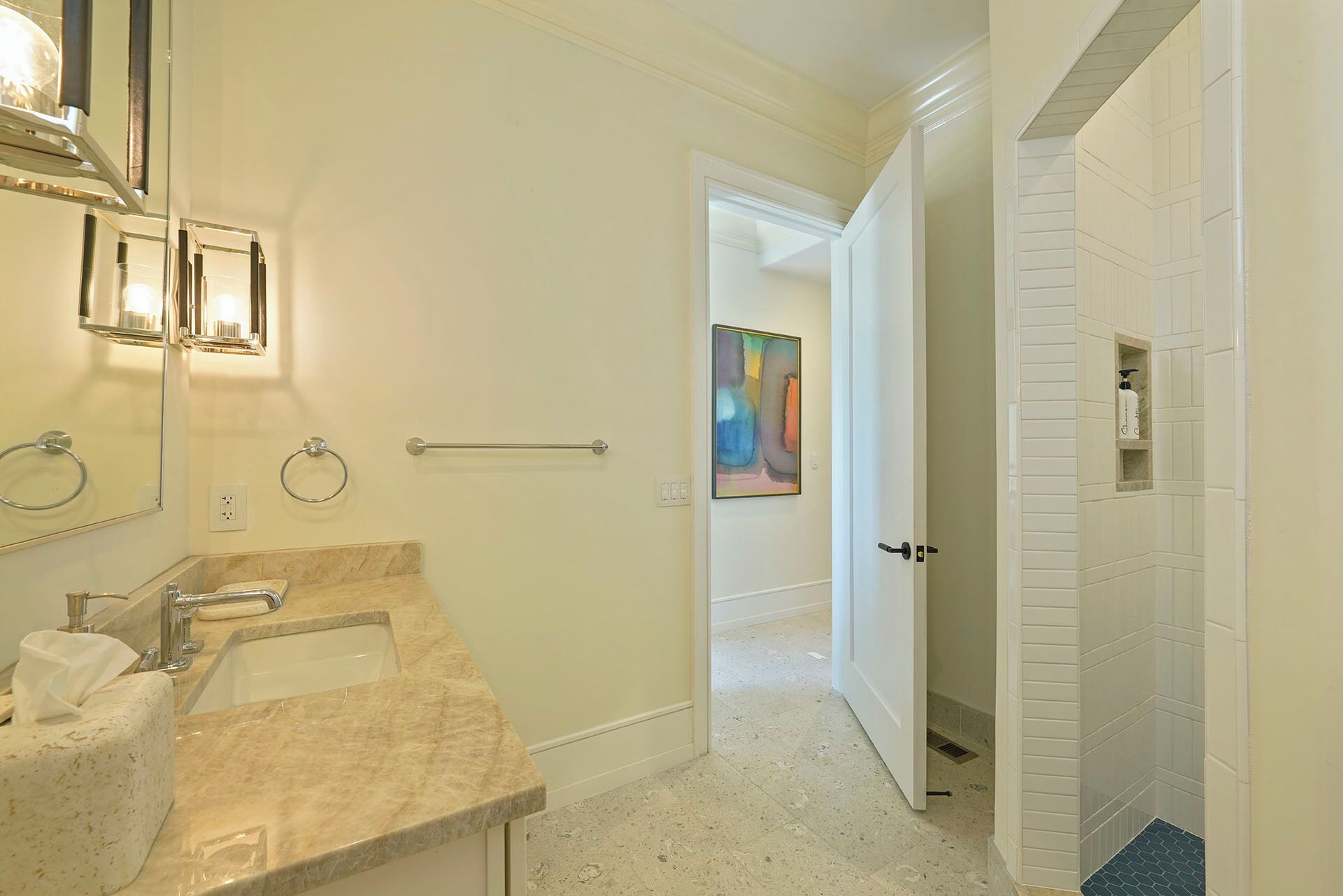 A bathroom with two sinks, a mirror, a towel rack, and a door leading to another room.