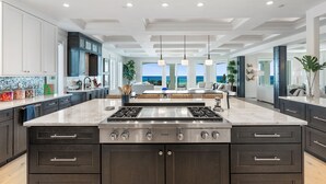 Una cucina moderna con un'isola grande, mobili scuri e vista sull'oceano.