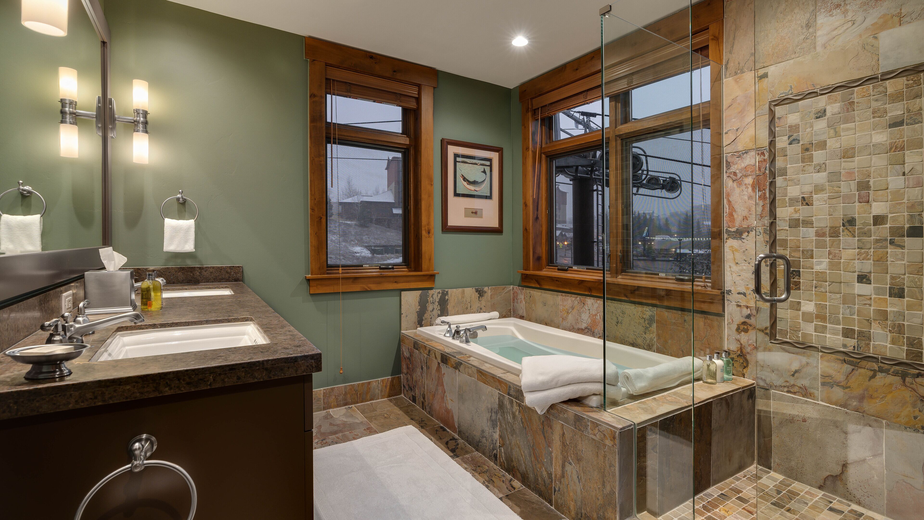A bathroom with two sinks, a bathtub, and a glass-enclosed shower.