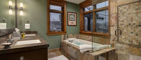A bathroom with two sinks, a bathtub, and a glass-enclosed shower.
