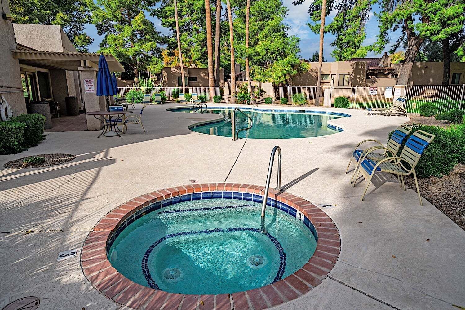 Un espace piscine comprenant deux piscines, un jacuzzi, des chaises longues et un coin salon abrité.