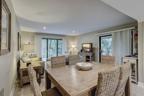 Enjoy meals in this dining area with a large table and six chairs, a TV, and a side table with a lamp.