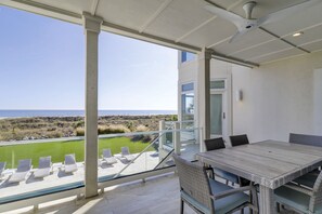 A balcony with a view of the beach, a table with chairs, and a glass railing. - 10 Curlew OCEANFRONT, 5 Bedroom w/ Private Heated Pool, Spa & Outdoor Kitchen (Hilton Head Island)