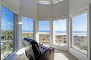 Habitación de esquina con amplias ventanas que ofrecen vistas a la playa y al océano.