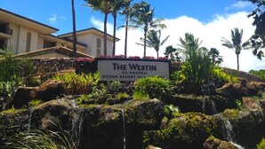 A sign for The Westin Ka'anapali Ocean Resort Village with a view of palm trees and a building in the background.