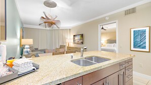 A modern hotel bathroom with a granite countertop, double sink, and a ceiling fan.