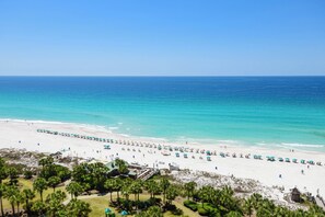 A beach with umbrellas and lounge chairs, a clear sky, and a view of the ocean. - Cozy beachfront condo w/private balcony & elevator in Destin! ☀🌺🐚 (Destin)