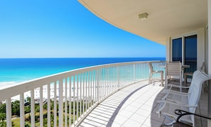 Un balcon avec vue sur l’océan, des balustrades blanches et une table avec des chaises.