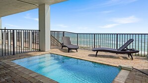 A pool area with two lounge chairs, a concrete ceiling, and a view of the ocean. - Luna Sol - Beachfront Duplex with Private Pool Area & Beach Access (Destin)