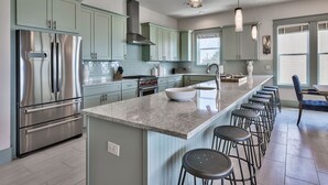A modern kitchen with a central island, stainless steel appliances, and light blue cabinetry. - Luna Sol - Beachfront Duplex with Private Pool Area & Beach Access (Destin)