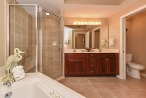 Un baño con cabina de ducha, bañera, tocador con espejo y un inodoro.