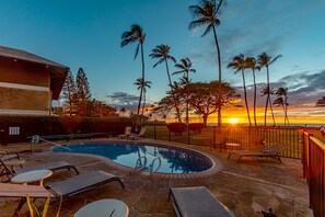 Una piscina con lettini e vista sul tramonto.