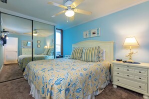 A bedroom with a bed, nightstands, a lamp, a ceiling fan, and a mirror.