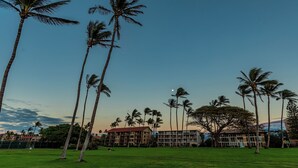 A hotel with multiple floors, a green lawn, and palm trees. - Leinaala Oceanfront #104  Ocean Front, A/C, Oceanfront  views, Remodeled! (Kihei)