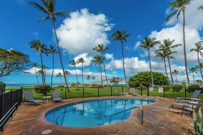 A swimming pool with lounge chairs and a view of the ocean.