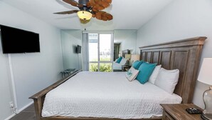 A bedroom with a bed, a ceiling fan, a television, and a view of the outdoors. - Modern Kitchen w/ Ocean & Harbor View- Upper Cottage, G32  North Coast Village (Oceanside)