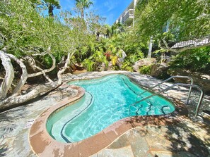 A swimming pool with a curved design, surrounded by lush greenery and a stone deck. - Modern Kitchen w/ Ocean & Harbor View- Upper Cottage, G32  North Coast Village (Oceanside)