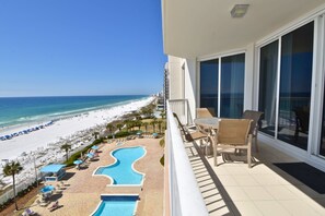 A balcony with a view of a beach and a pool.