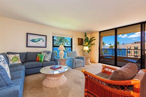 A living room with a sofa, armchairs, a coffee table, and a view of the beach through large windows. - Oceanview Penthouse Condo - Spacious & Serene Sanctuary - Sugar Beach #PH12 (Kihei)