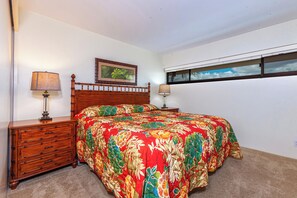 Quarto com cama de madeira, mesa de cabeceira, cômoda e janela com persianas.