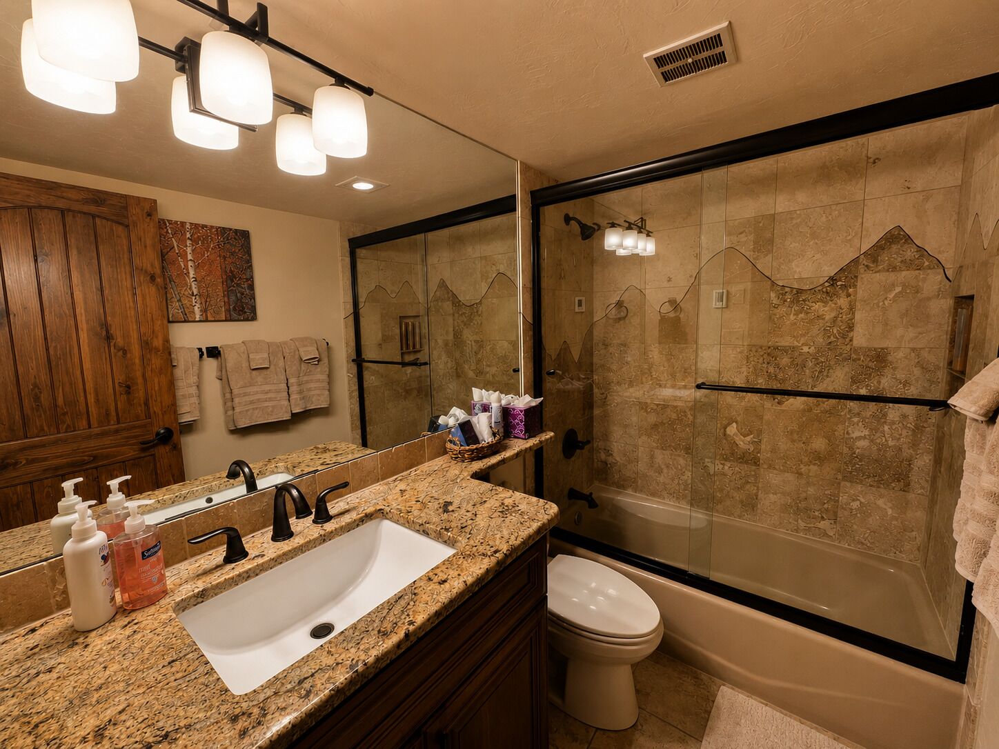 A bathroom with a granite countertop, a sink, a toilet, a shower with a glass door, and a mirror.