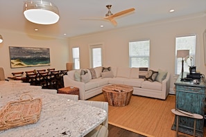 A living room with a white sofa, a round coffee table, and a dining area with a table and chairs.