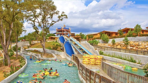 Un parque acuático con toboganes, balsas hinchables y una cabaña de madera.