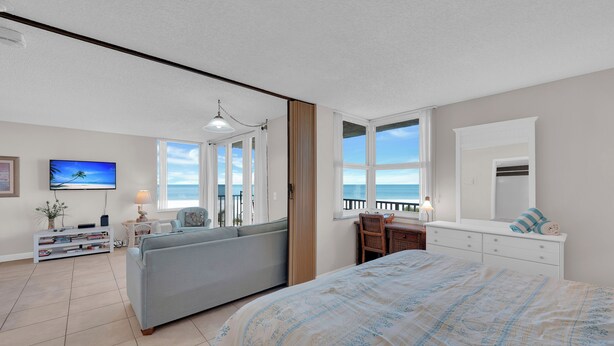 A bedroom with a bed, a sofa, a desk, and a TV. - Beachfront Condo Offers Fun and Sun At Bargain Price! PET FRIENDLY! (Fort Myers Beach)