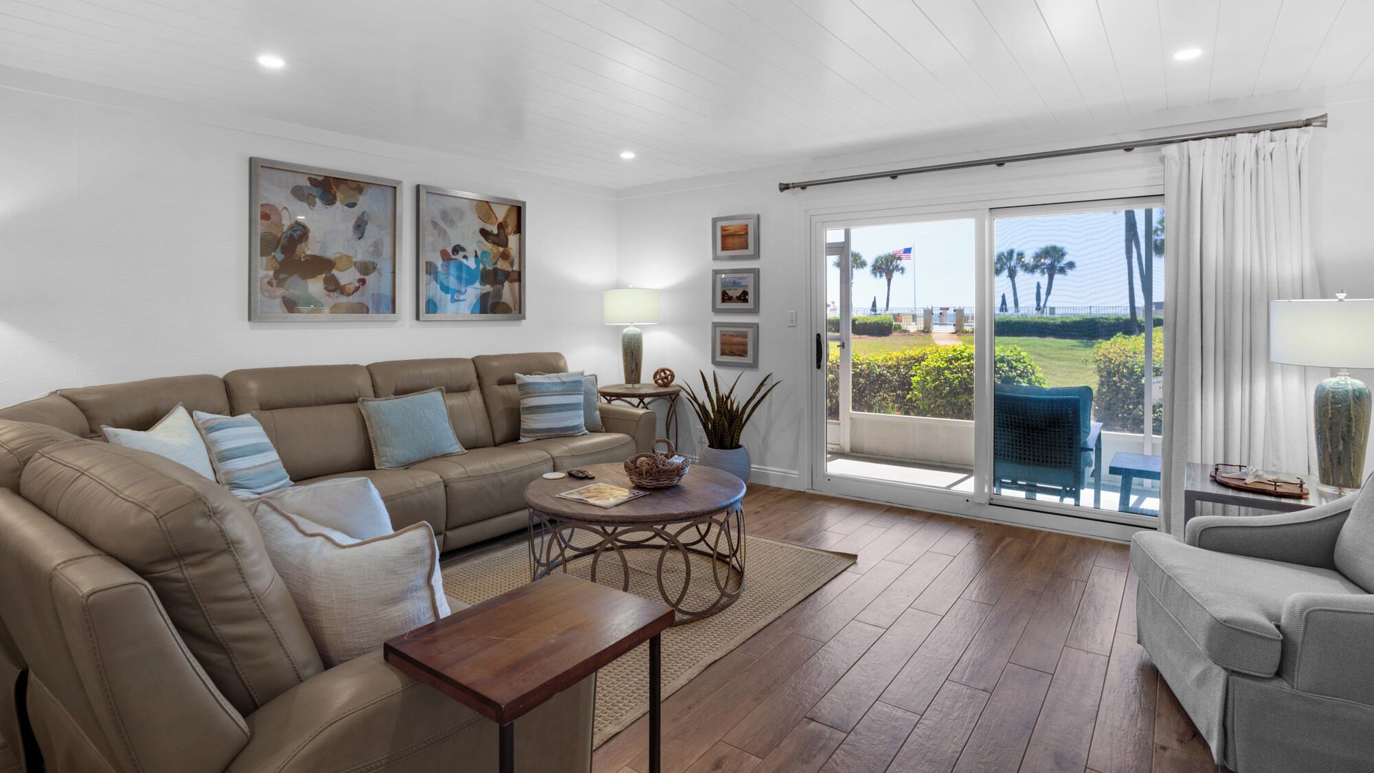 A spacious living room with a leather sofa, a coffee table, and a view of the outdoors through large sliding glass doors.