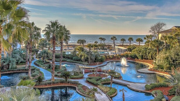 Ein Resort mit mehreren Pools, Palmen und Blick auf den Ozean.