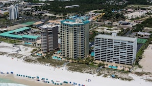 Un hotel costero con varios edificios altos, una playa con sombrillas y una piscina.