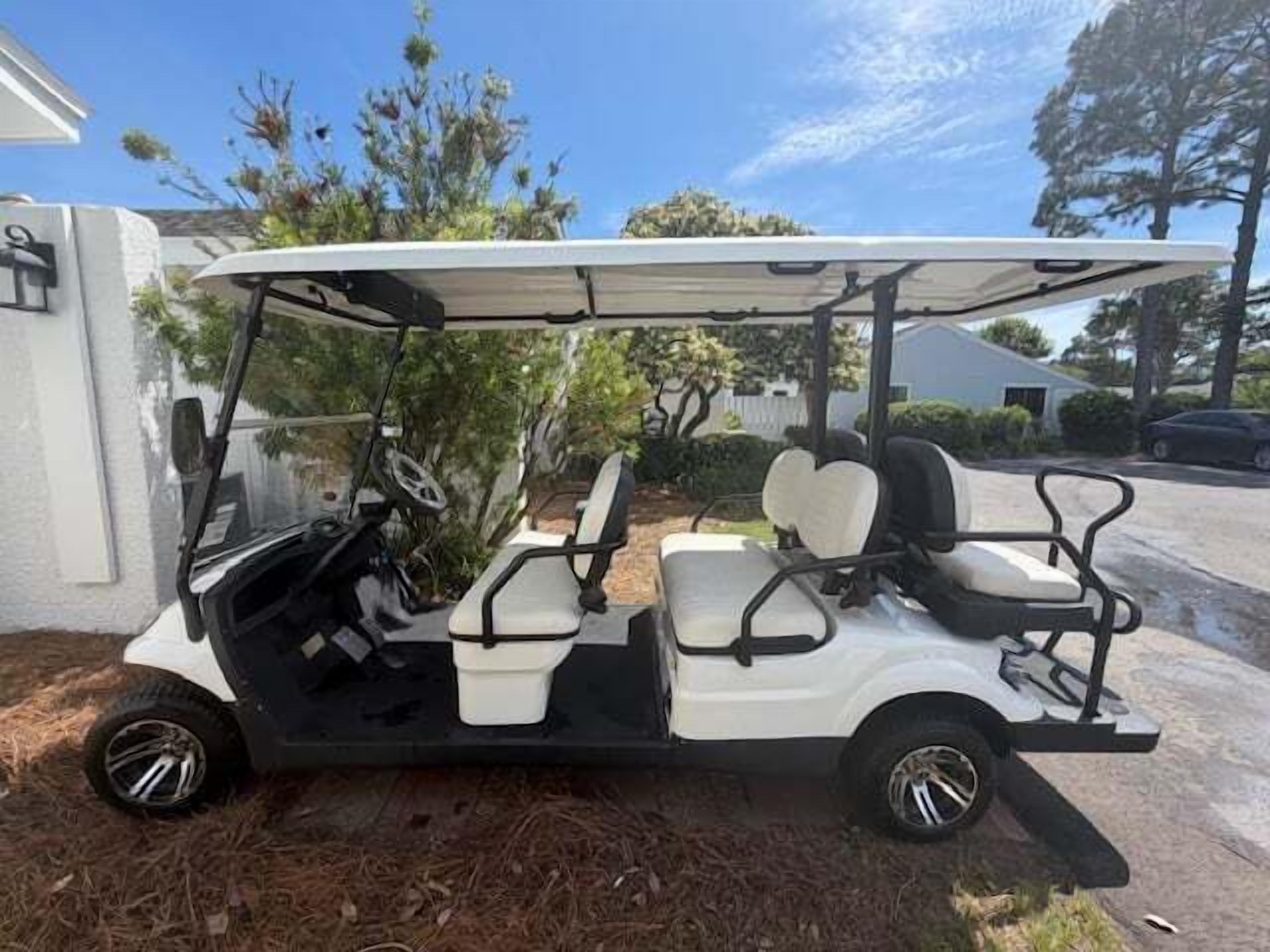 A golf cart parked on a driveway with a house in the background.