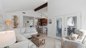 A spacious living area with a sofa, coffee table, and armchairs, leading to a kitchen and dining area. - Golf Cart! Pet-friendly! Linkside Village 435! (Miramar Beach)