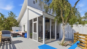 A covered outdoor area with a patio, a blue lounge chair, and a white building with glass doors. - Golf Cart! Pet-friendly! Linkside Village 435! (Miramar Beach)