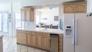 A kitchen with wooden cabinets, a white refrigerator, a dishwasher, and a water dispenser. - Gulf front! Pet Friendly! Beach House 30A Unit #2 - Gulf Front, Dune Allen Beach (Santa Rosa Beach)