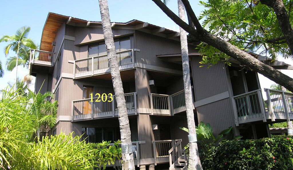 Un hotel de varios pisos con balcones, rodeado de vegetación tropical.