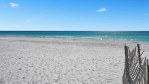 Ein Strand mit weißem Sand und einer Holzlattenzaun.