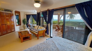 Una camera da letto con un letto, un divano, un tavolino e un balcone vista oceano.