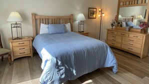 Een slaapkamer met een bed, nachtkastjes, een dressoir, een plafondventilator en een spiegel.