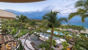 A resort with a pool area, palm trees, and a view of the ocean. - Best of Wai'ula'ula - Beautiful Decor, Ocean View, Resort Access! (Kamuela)