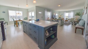 Een ruime keuken met een groot schiereiland, een eethoek met stoelen, en een zithoek met bank en salontafel.
