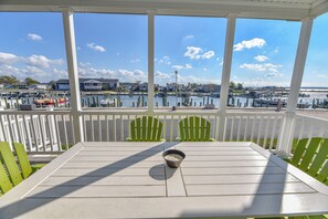 A covered outdoor seating area with a table and chairs, overlooking a marina with boats and houses.